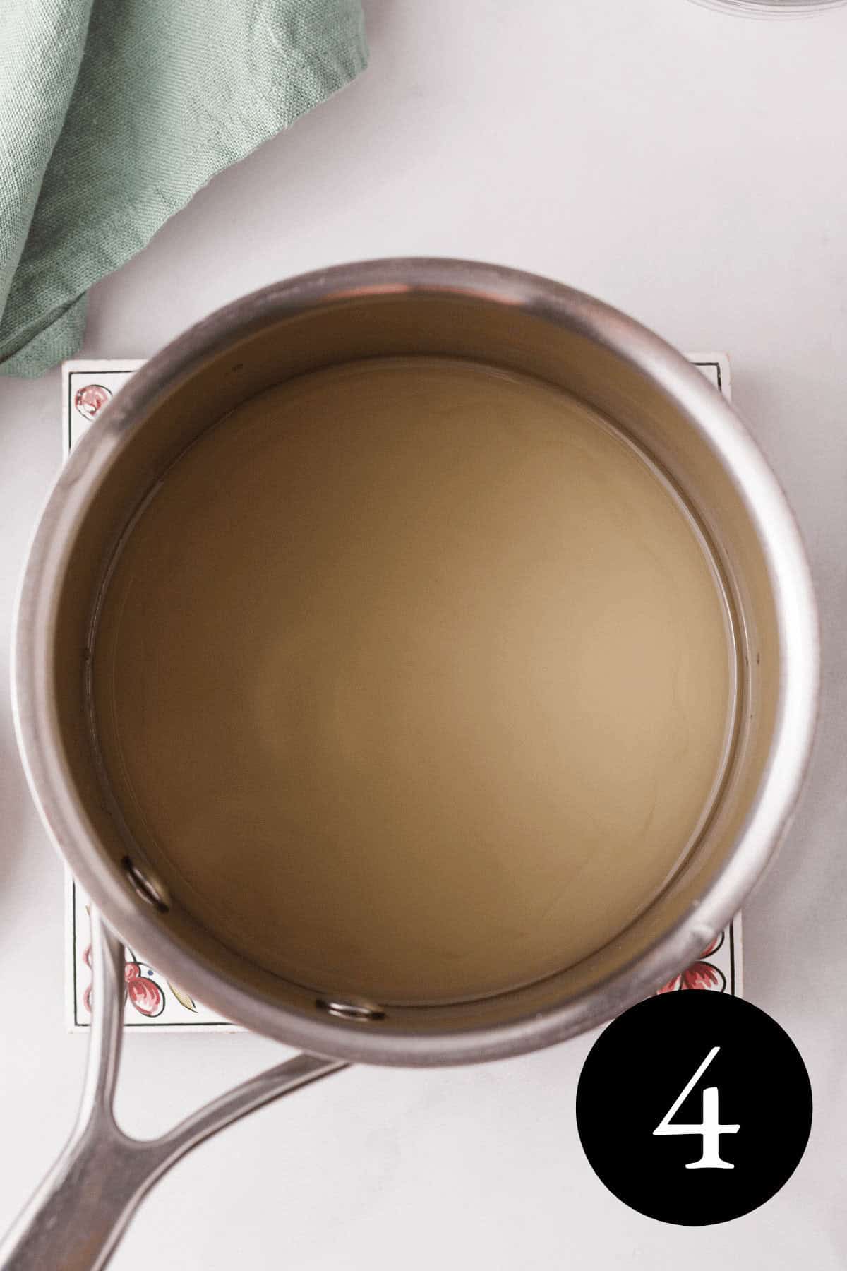 overhead image of thyme simple syrup in saucepan with a cloudy appearance from adding arrowroot powder