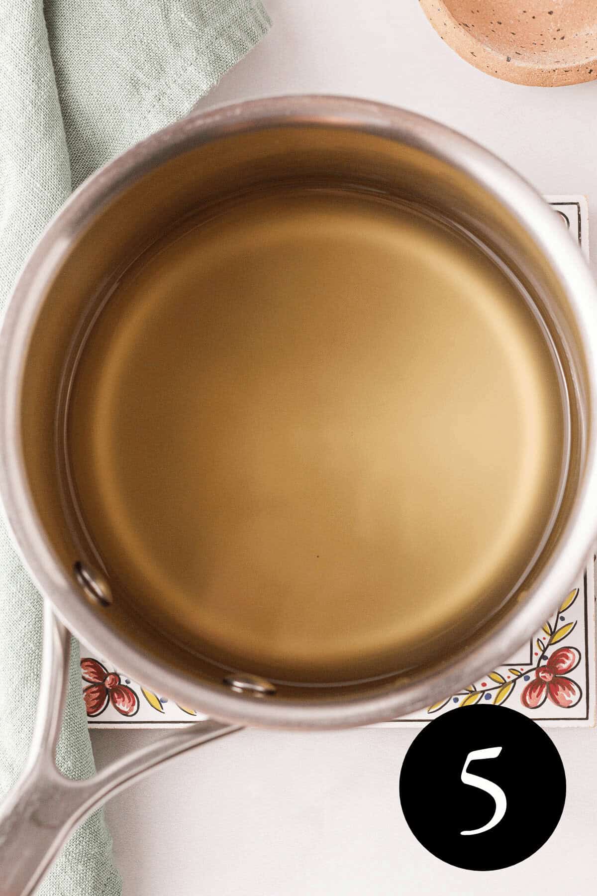 overhead image of thyme simple syrup liquid after turning more clear in saucepan