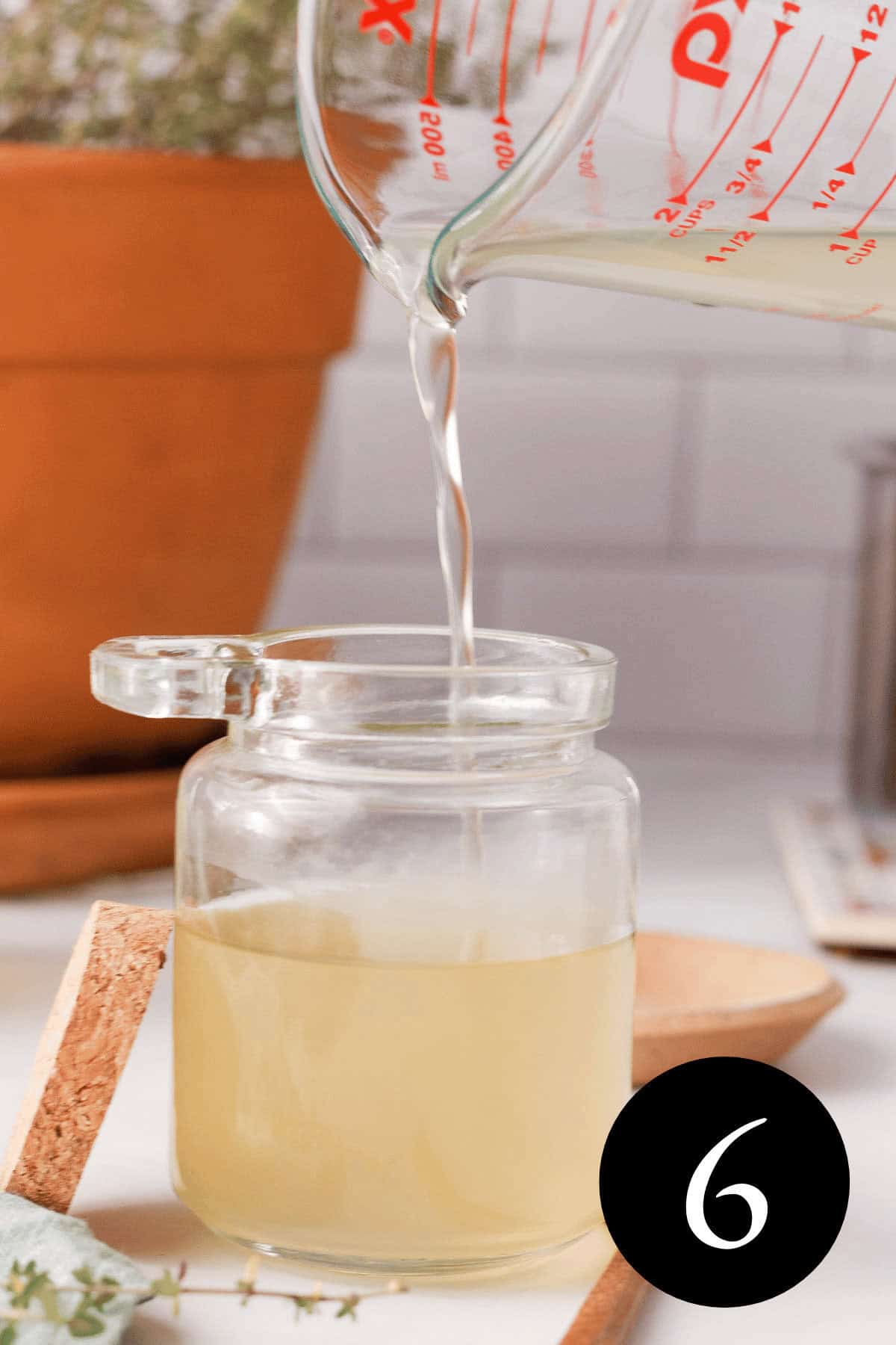 side image of thyme simple syrup pouring into a glass jar with a pot of thyme growing in background