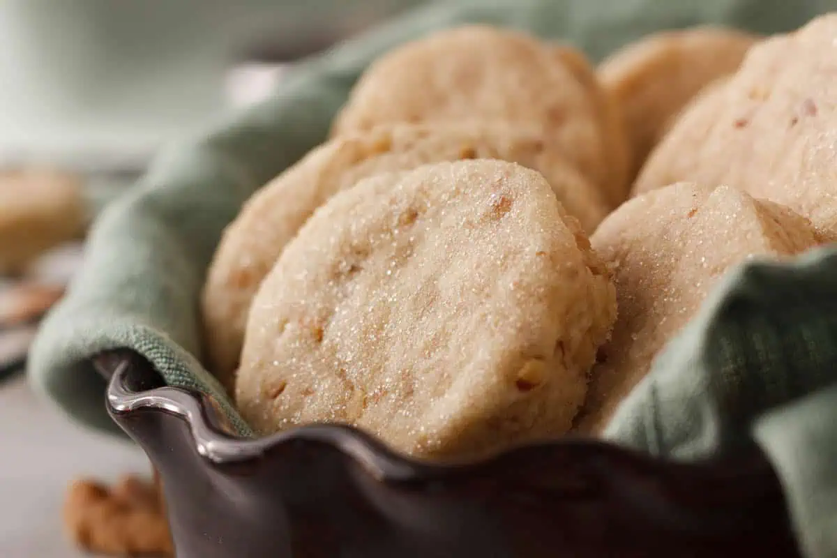 closeup of shortbread cookies in serving dish lined with a green dish towel showing the shimmer of the granulated sugar coating