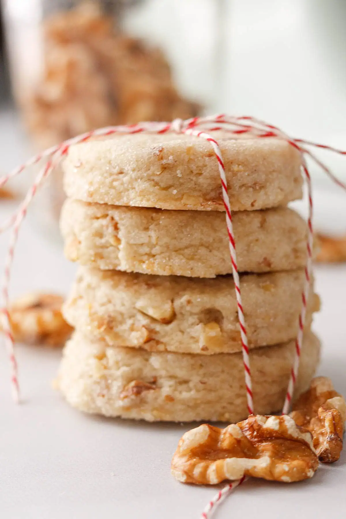 closeup of stacked shortbread cookies tied with ribbon and accented by walnut halves in foreground and background