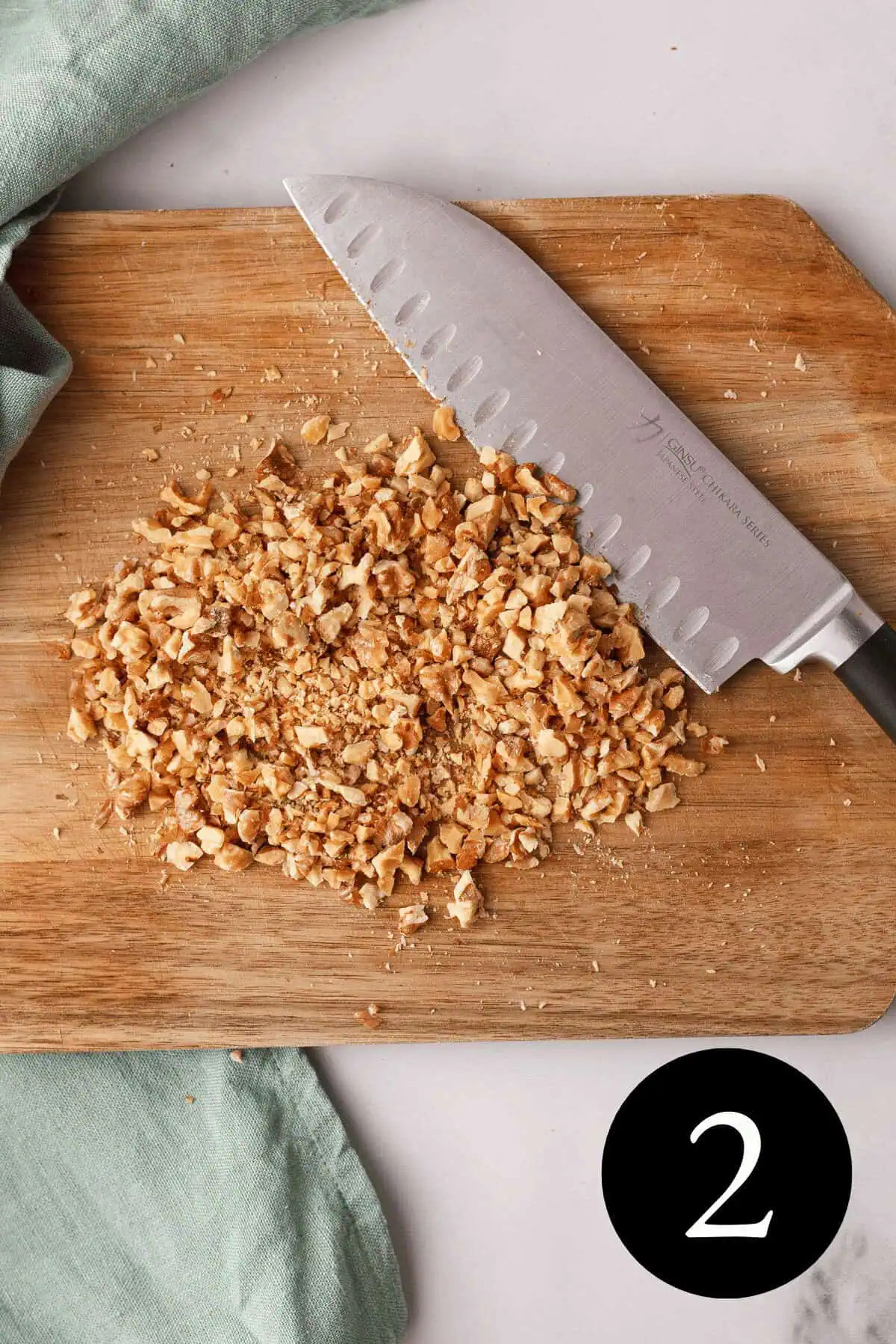 overhead image of chopped walnuts on cutting board with knife resting along the side