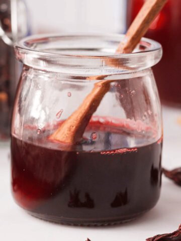 closeup of hibiscus simple syrup in glass jar with wooden spoon resting in jar