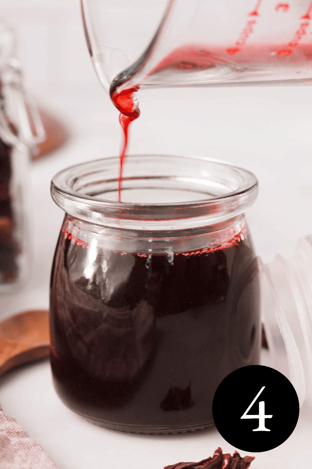 closeup of hibiscus simple syrup pouring into glass jar