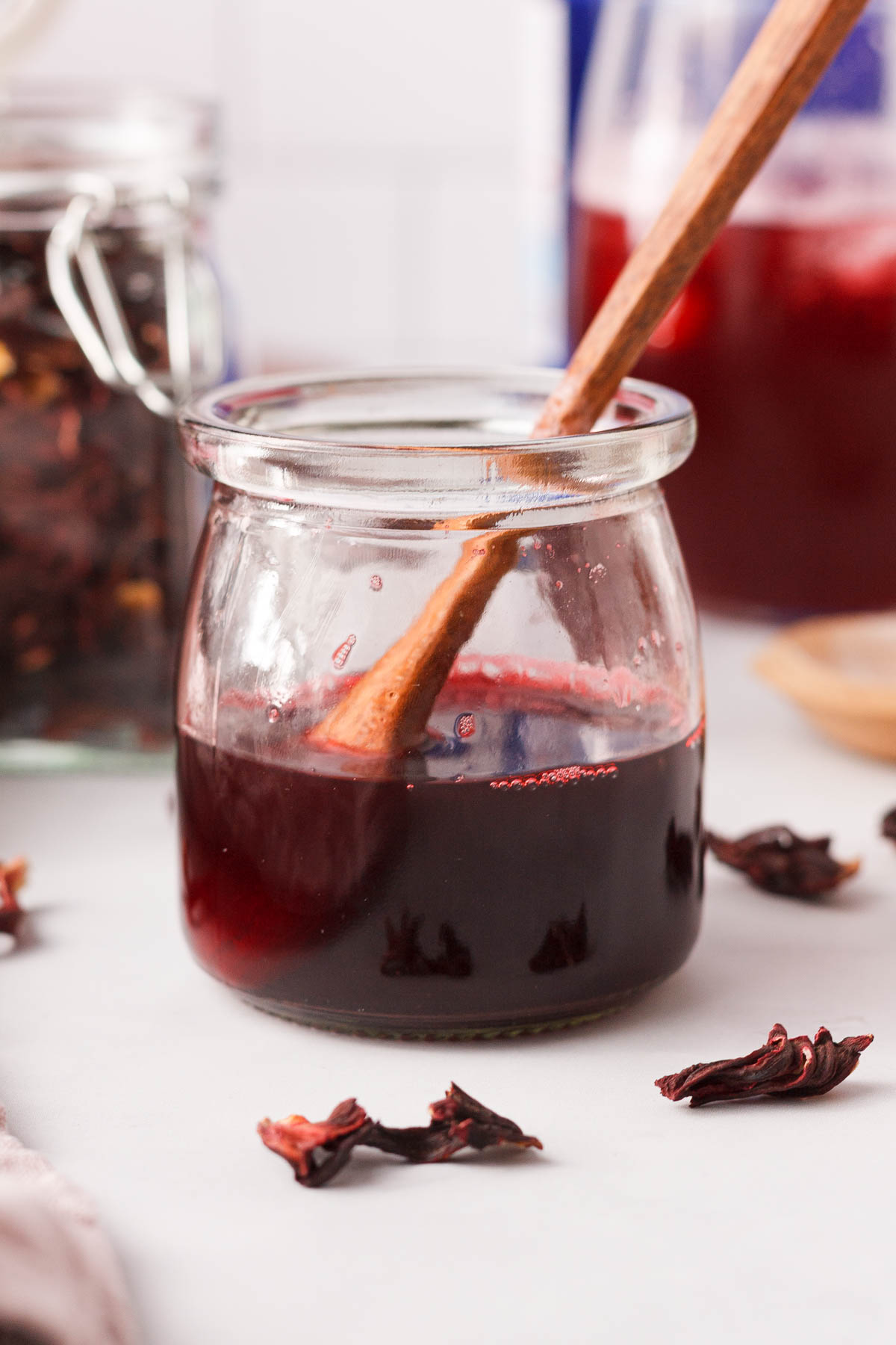 closeup of jar with hibiscus simple syrup with wood spoon propped in the jar