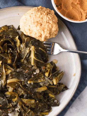 overhead image of miso collard greens on plate with beer biscuit and a container of white miso peeking in from the top right corner