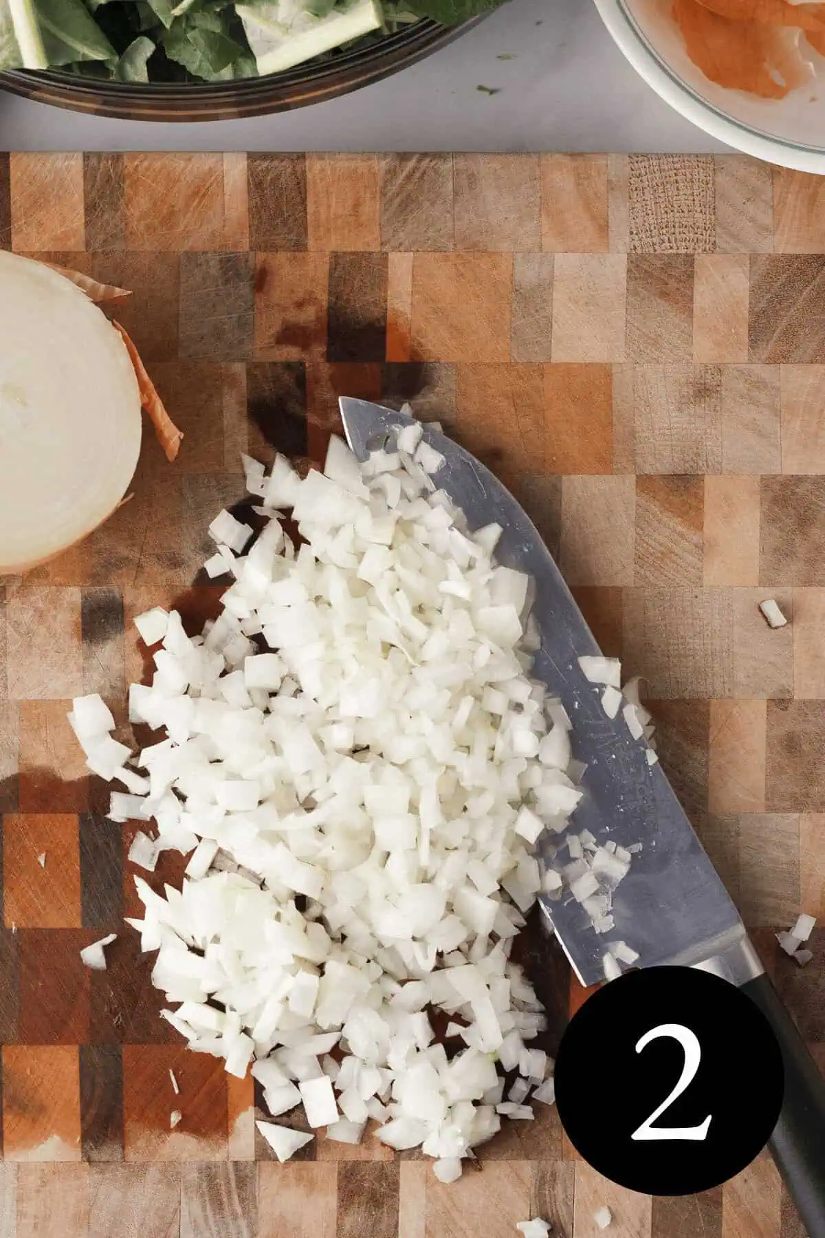 overhead image of diced yellow onion on cutting board with the number two in the bottom right corner