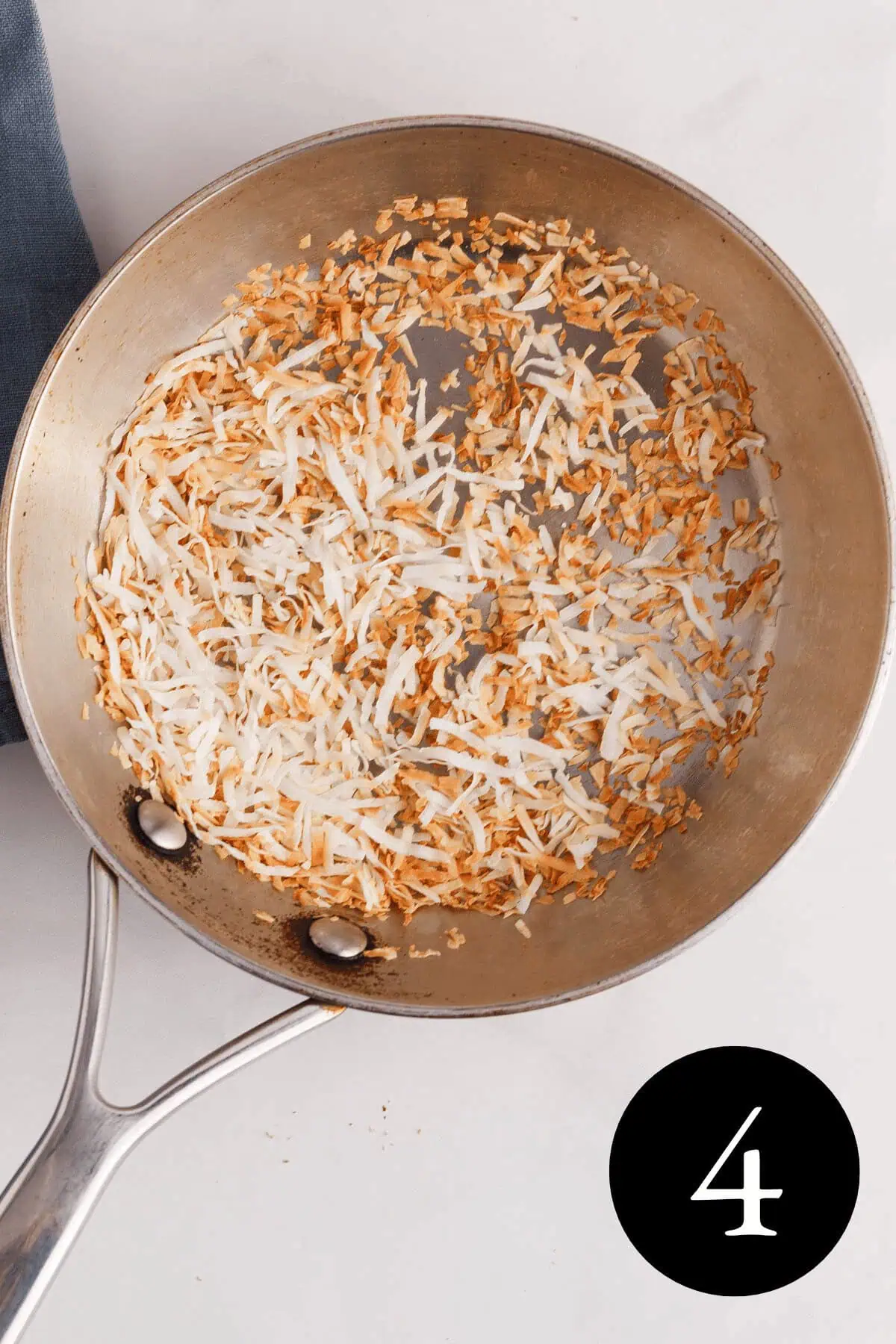 overhead image of shredded coconut toasted in skillet with number four in the bottom right corner