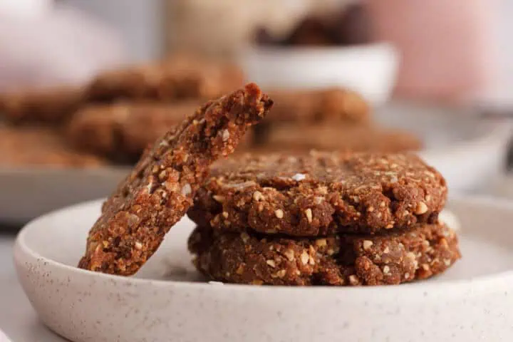 closeup of peanut butter date cookies on plate with a cookie broken in half and propped on the other cookies
