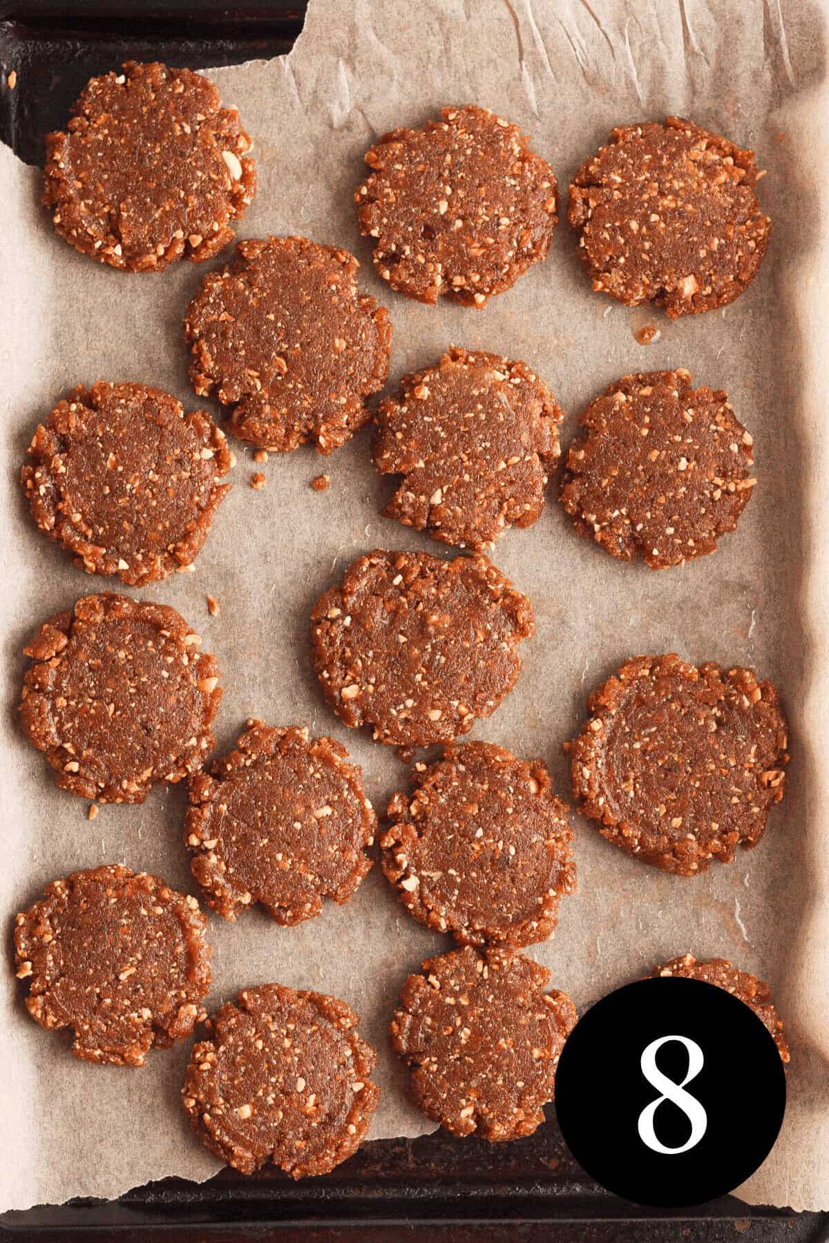 overhead image of peanut butter date cookies pressed into cookie shapes on baking sheet with number eight in the bottom right corner