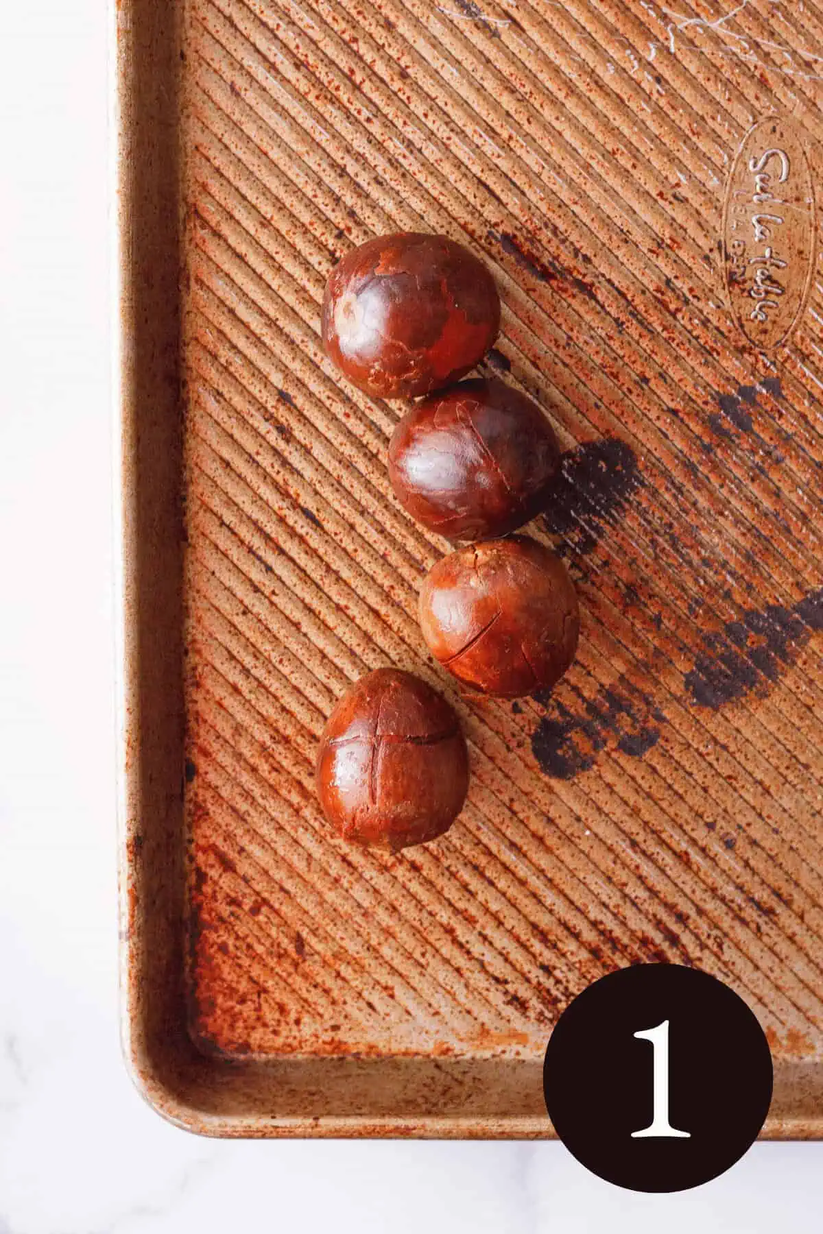 overhead image of avocado pits on baking sheet with number 1 in the bottom right corner