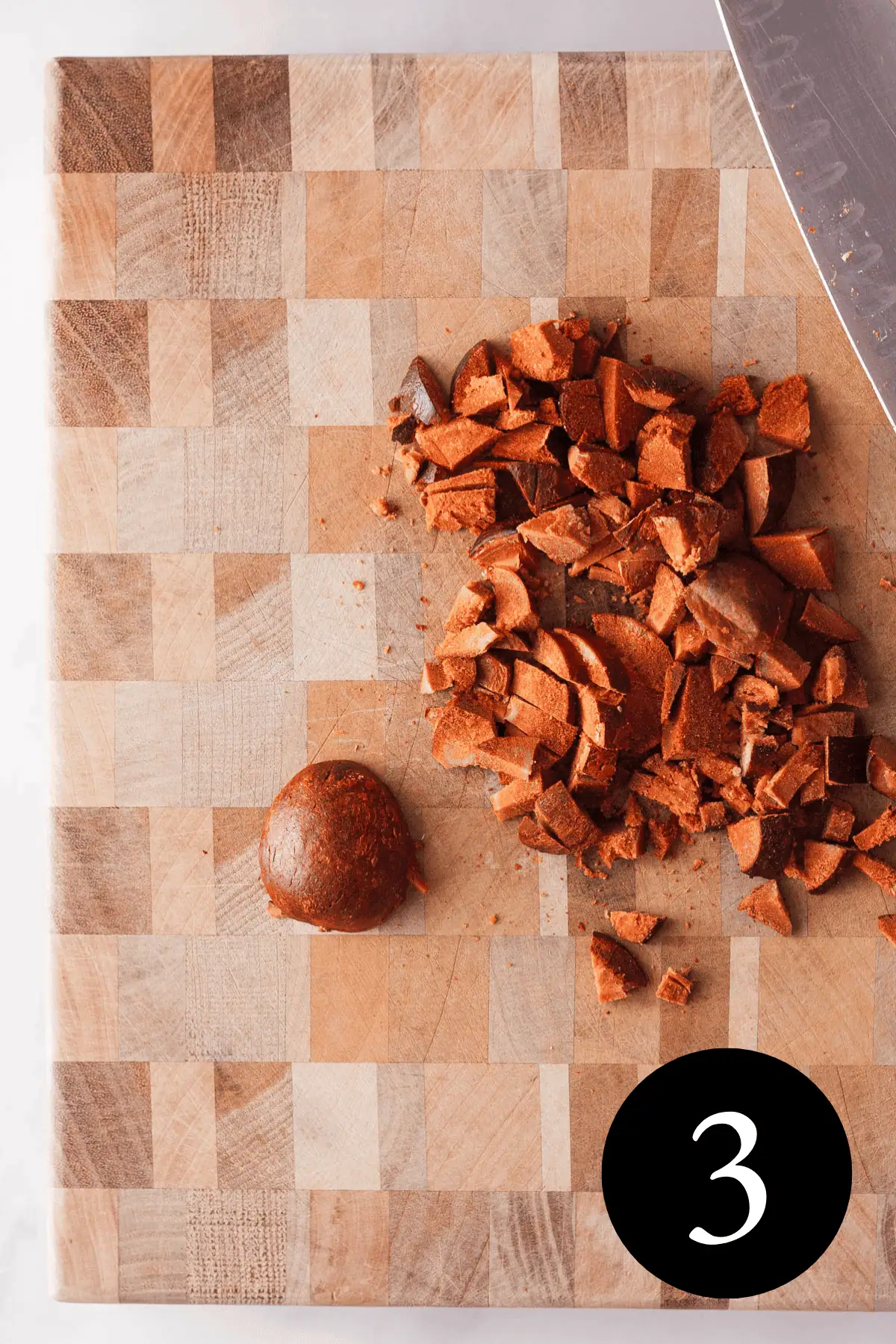 overhead image of avocado seeds chopped on cutting board with knife in the top right corner and number three in the bottom right corner