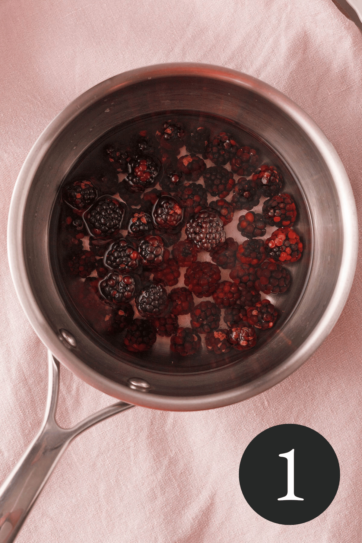 overhead image of blackberries floating in saucepan with water and number one in bottom right corner