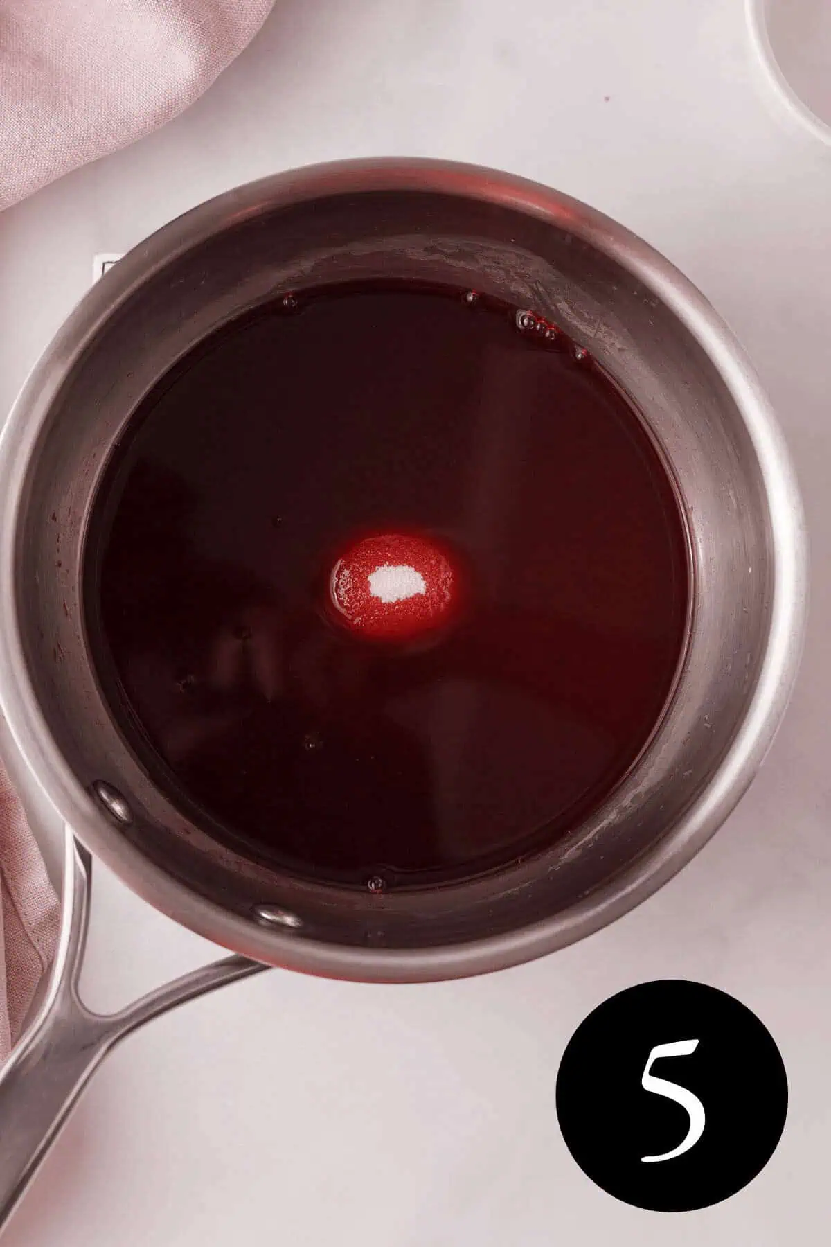 overhead image of blackberry simple syrup in saucepan with clump of sugar in the middle and number five in the bottom right corner