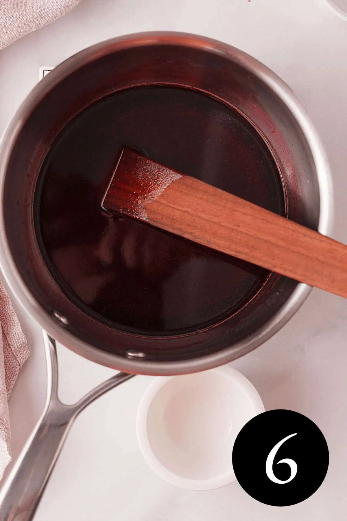 overhead image of complete blackberry simple syrup liquid in saucepan with number six in bottom right corner