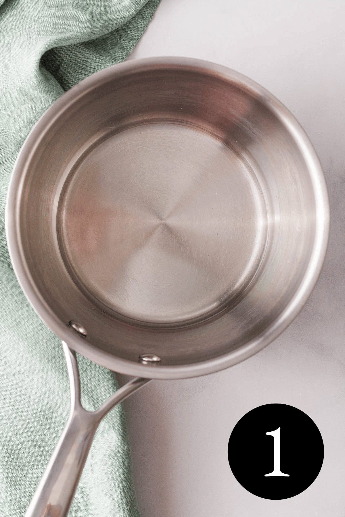 overhead closeup of melted coconut oil in small saucepan with number one in bottom right corner