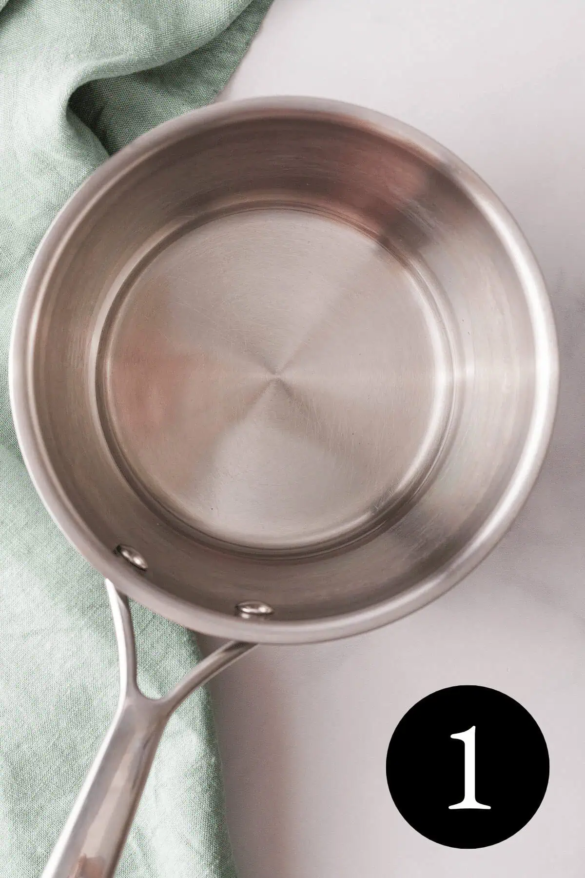 overhead closeup of melted coconut oil in small saucepan with number one in bottom right corner