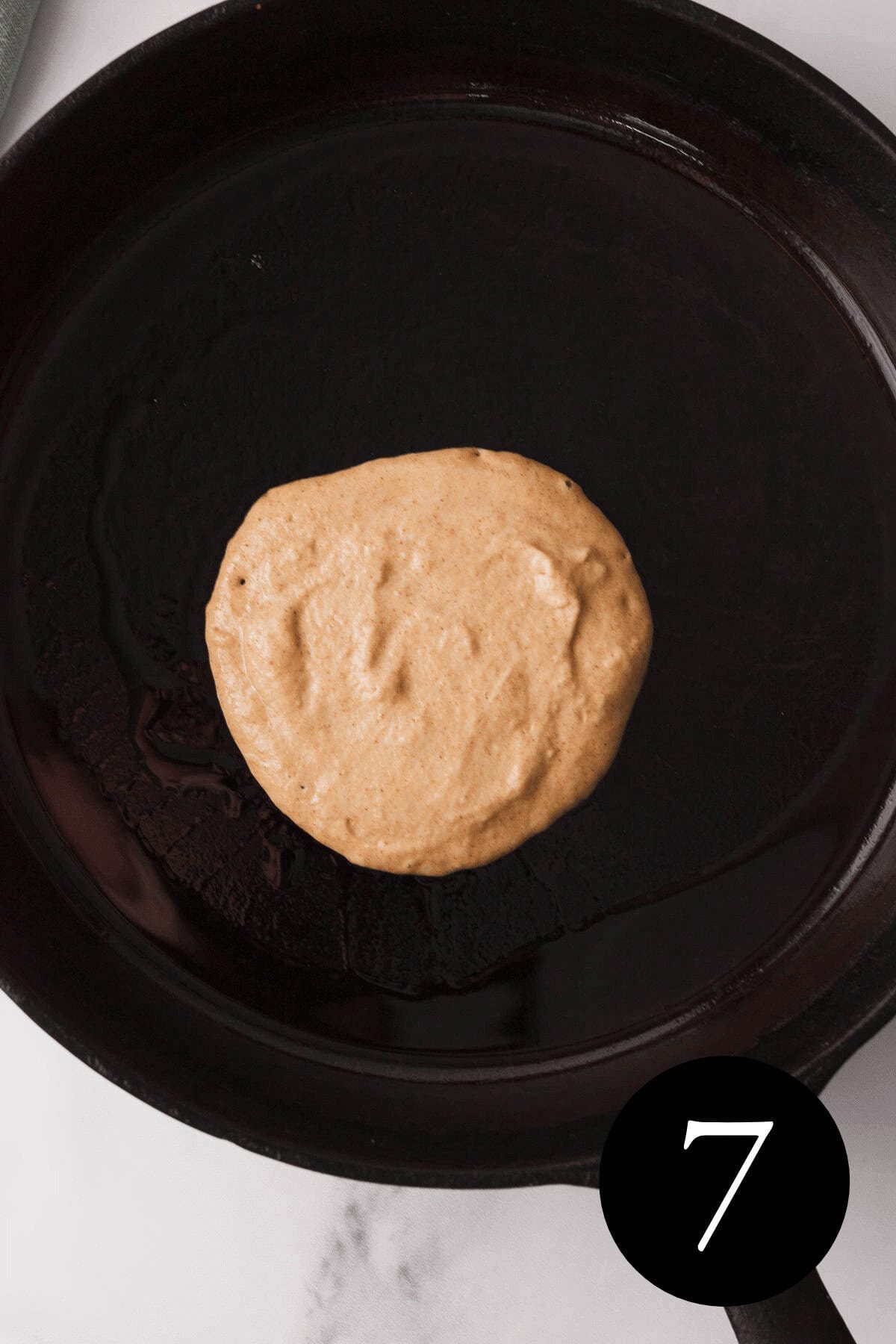 overhead image of pancake in cast iron skillet with number seven in bottom right corner