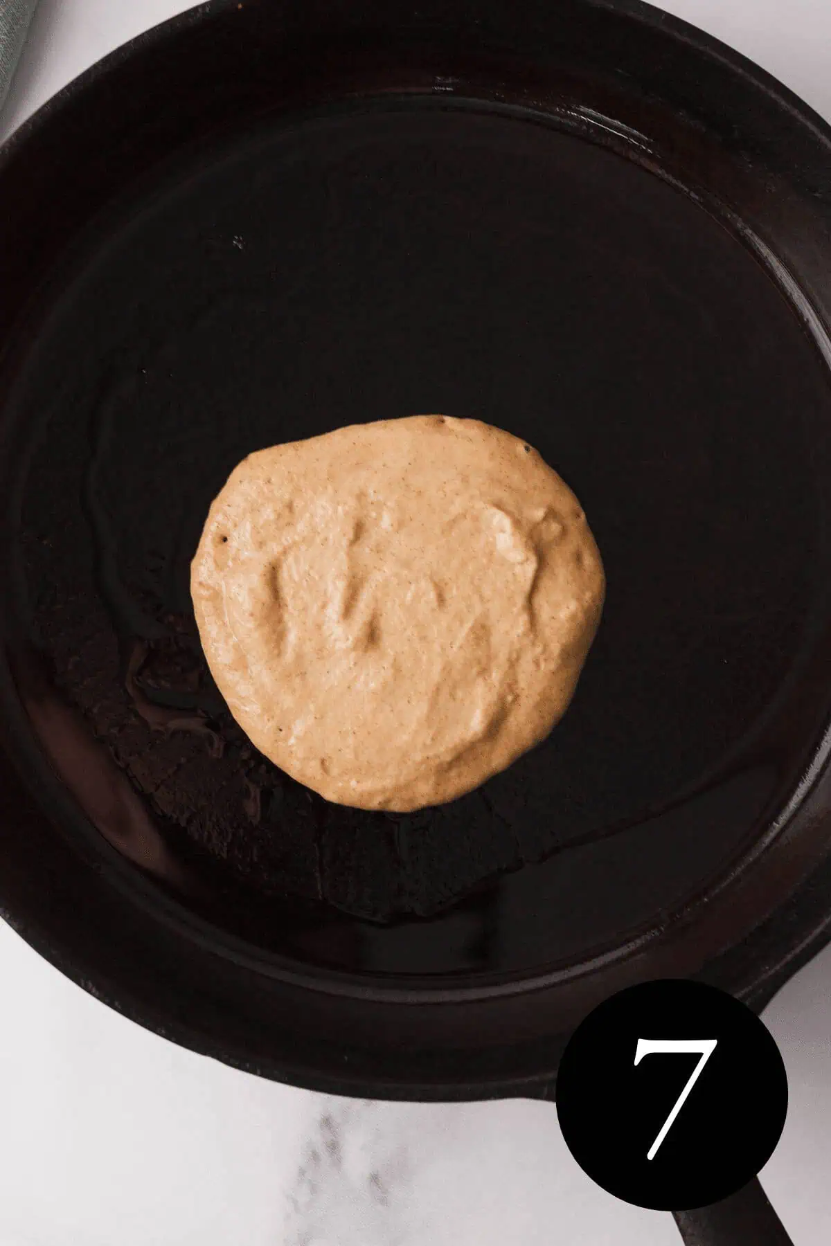 overhead image of pancake in cast iron skillet with number seven in bottom right corner