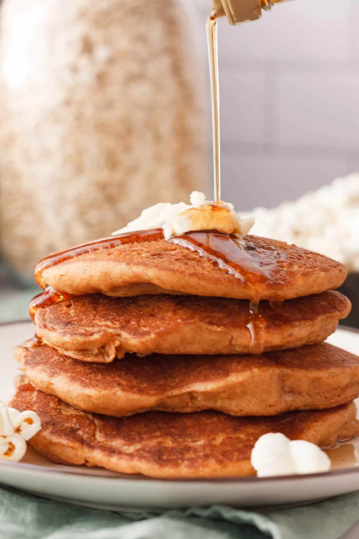 closeup side shot of a stack of popcorn pancakes with syrup pouring over the top