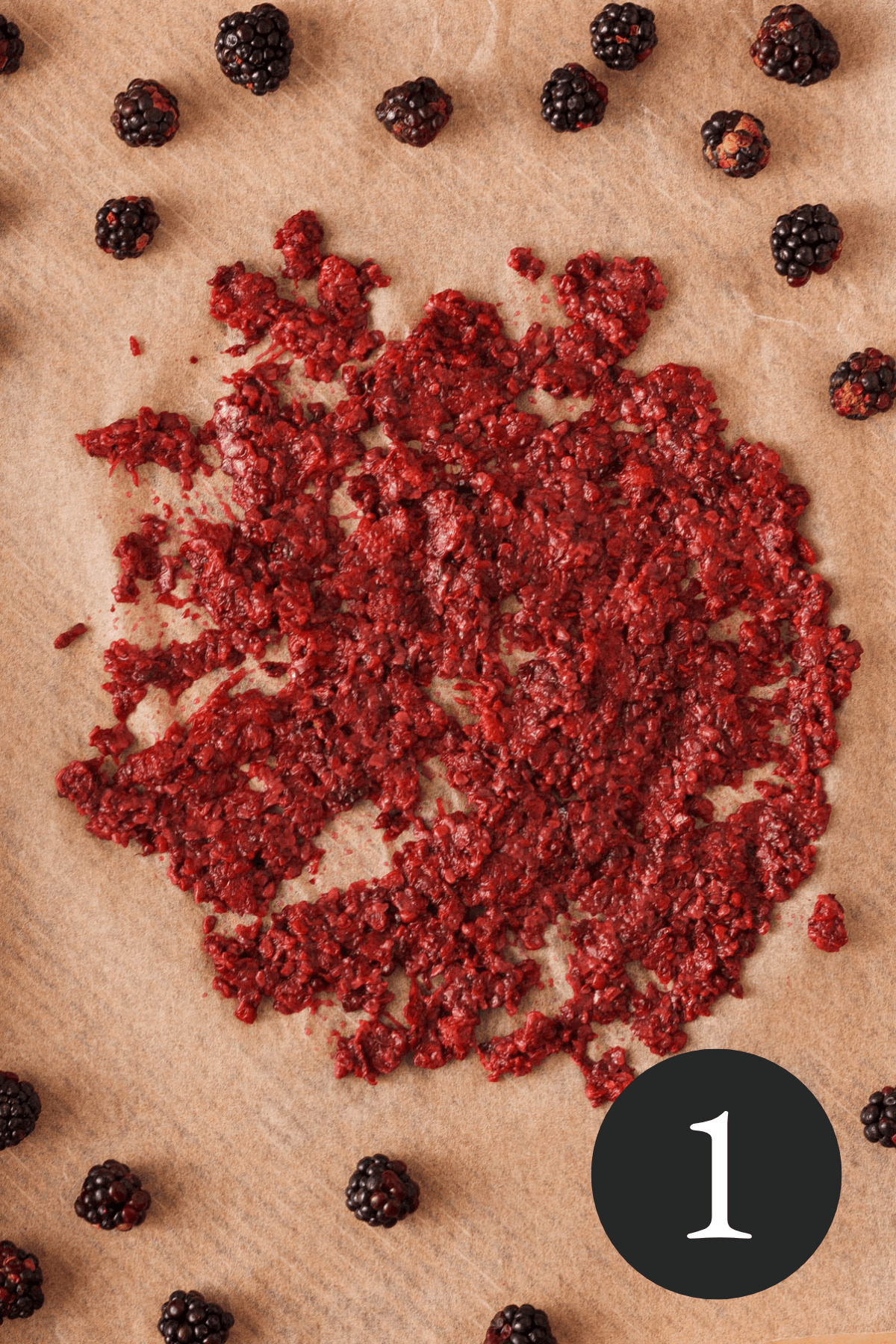 overhead image of blackberry pulp on parchment paper with whole blackberries surrounding the pulp and number one in the bottom right corner