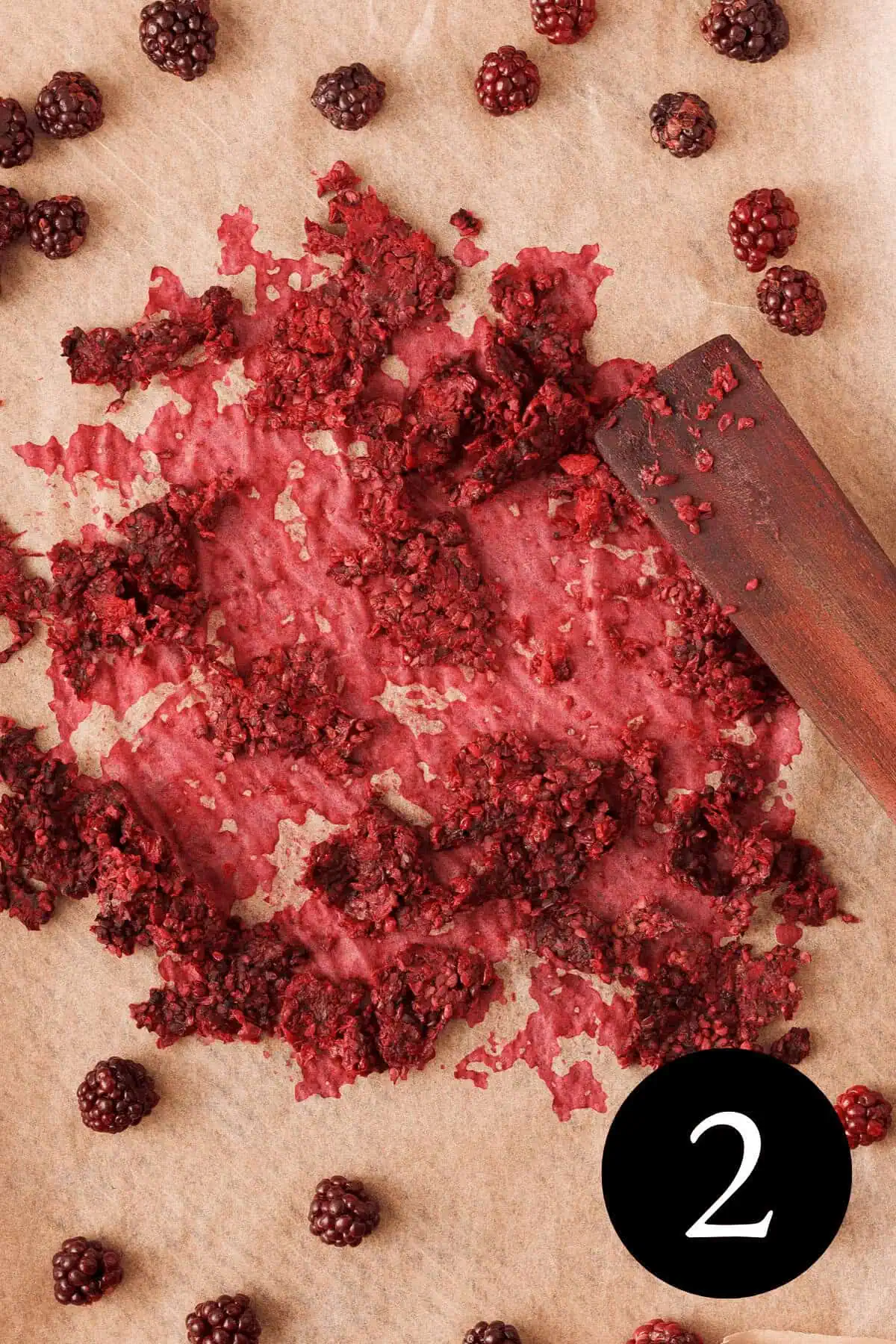 overhead image of blackberry pulp and blackberries on parchment paper after being stirred and number 2 in the bottom right corner
