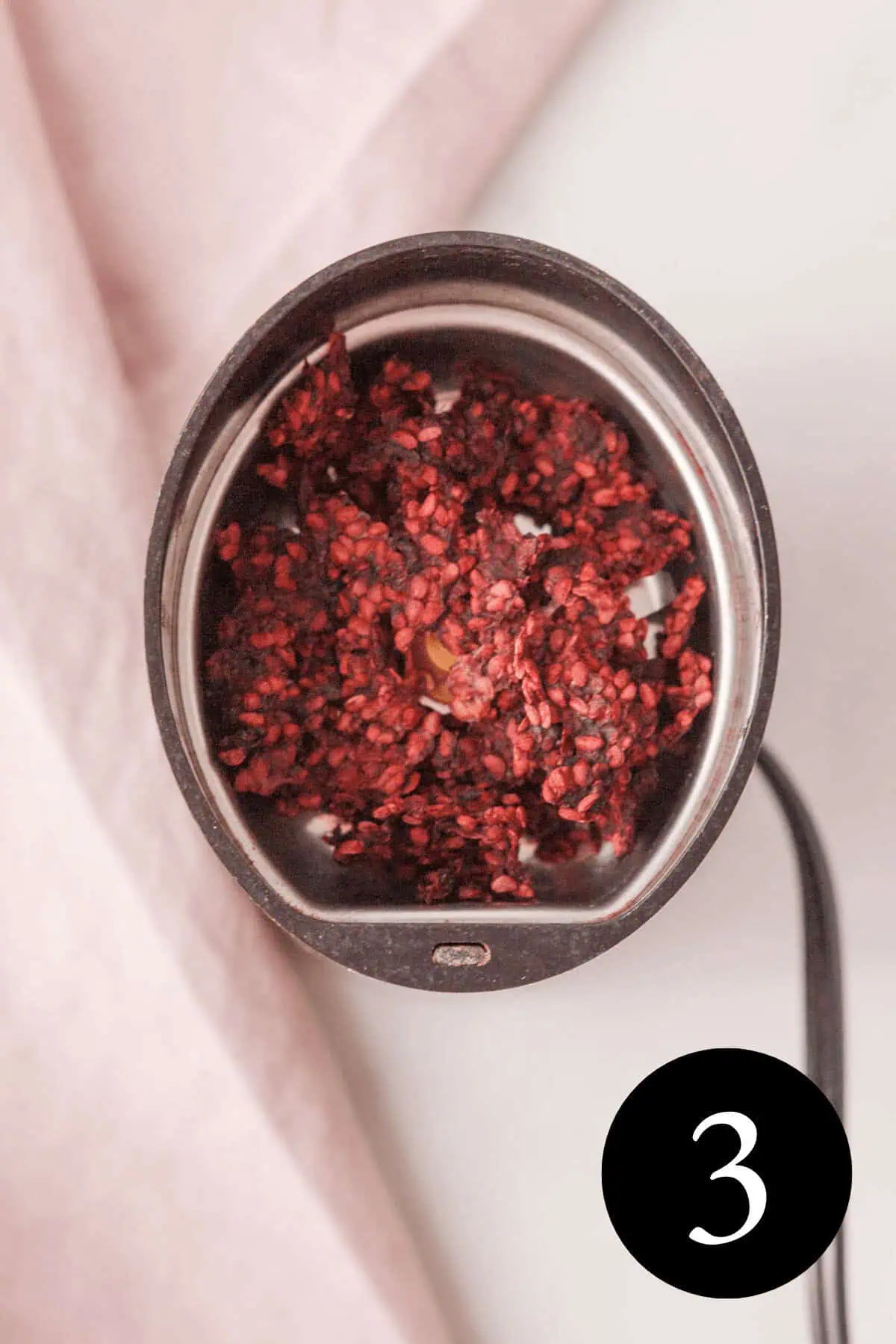 overhead image of dried blackberry pulp in spice grinder with number 3 in the bottom right corner