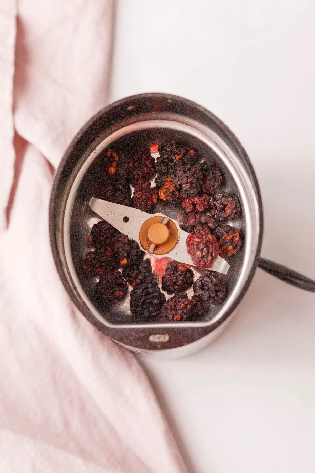 overhead image of dried whole blackberries in spice grinder