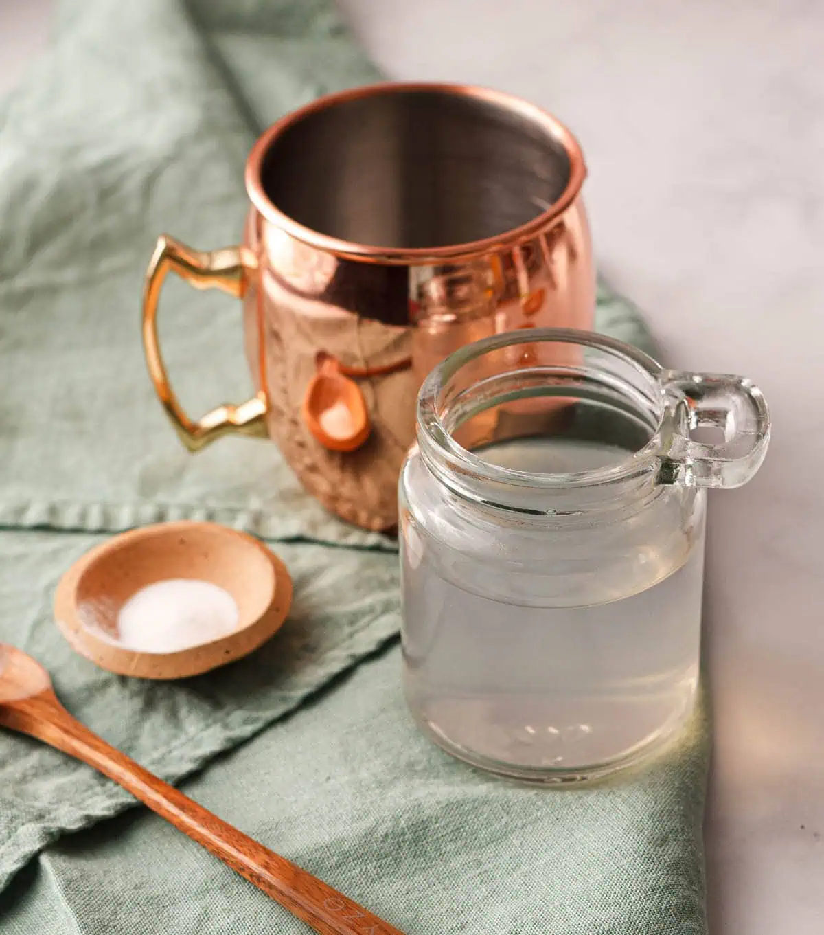closeup of jar of sugar free simple syrup with moscow mule mug and pure stevia extract on green tea towel