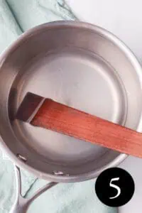 overhead image of liquid in saucepan with wood spatula and number five in the bottom right corner