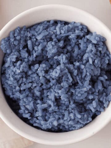 overhead closeup of butterfly pea rice in white bowl