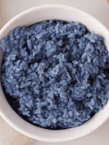 overhead closeup of butterfly pea rice in white bowl