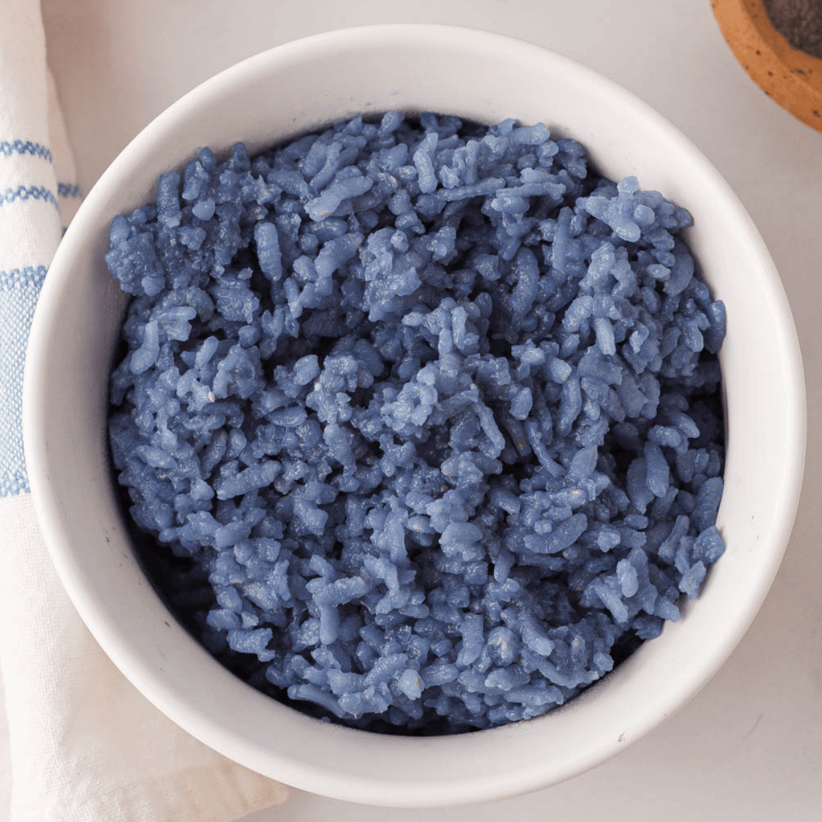 overhead closeup of butterfly pea rice in white bowl