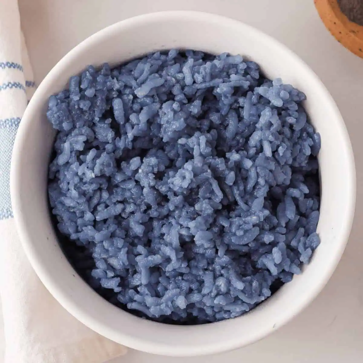 overhead closeup of butterfly pea rice in white bowl