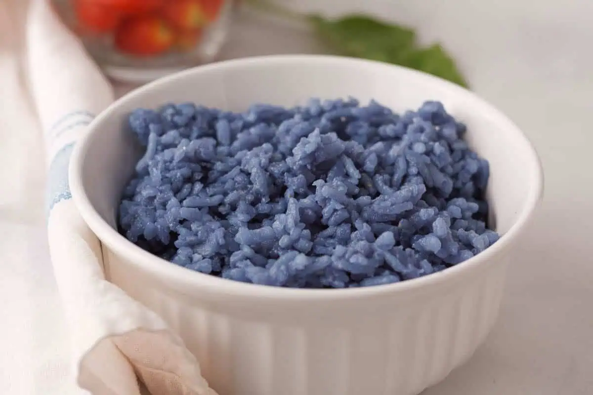 closeup of blue butterfly pea rice in white bowl