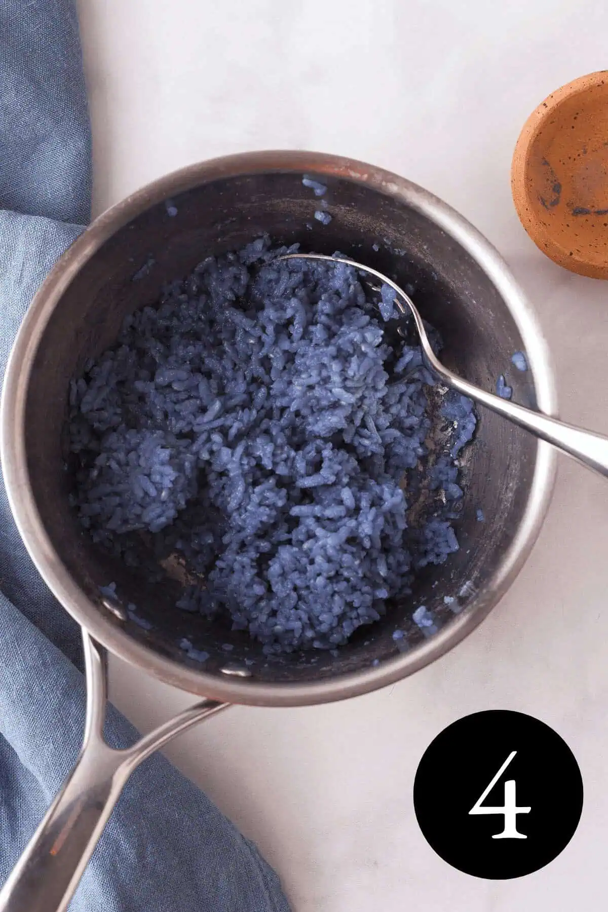 overhead image of butterfly pea rice in saucepan with number four in bottom right corner