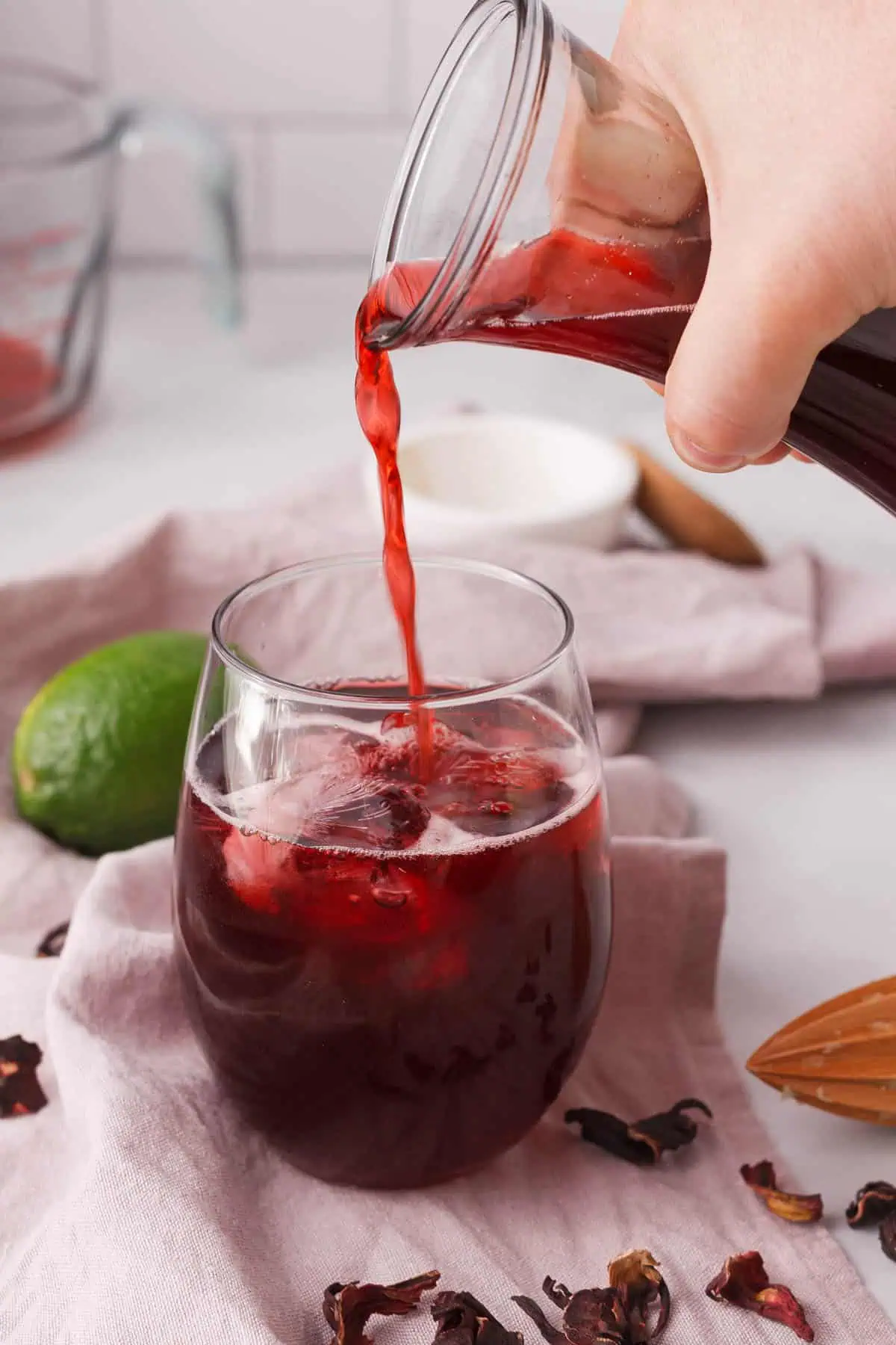 pouring hibiscus tea with cinnamon into a glass on kitchen counter