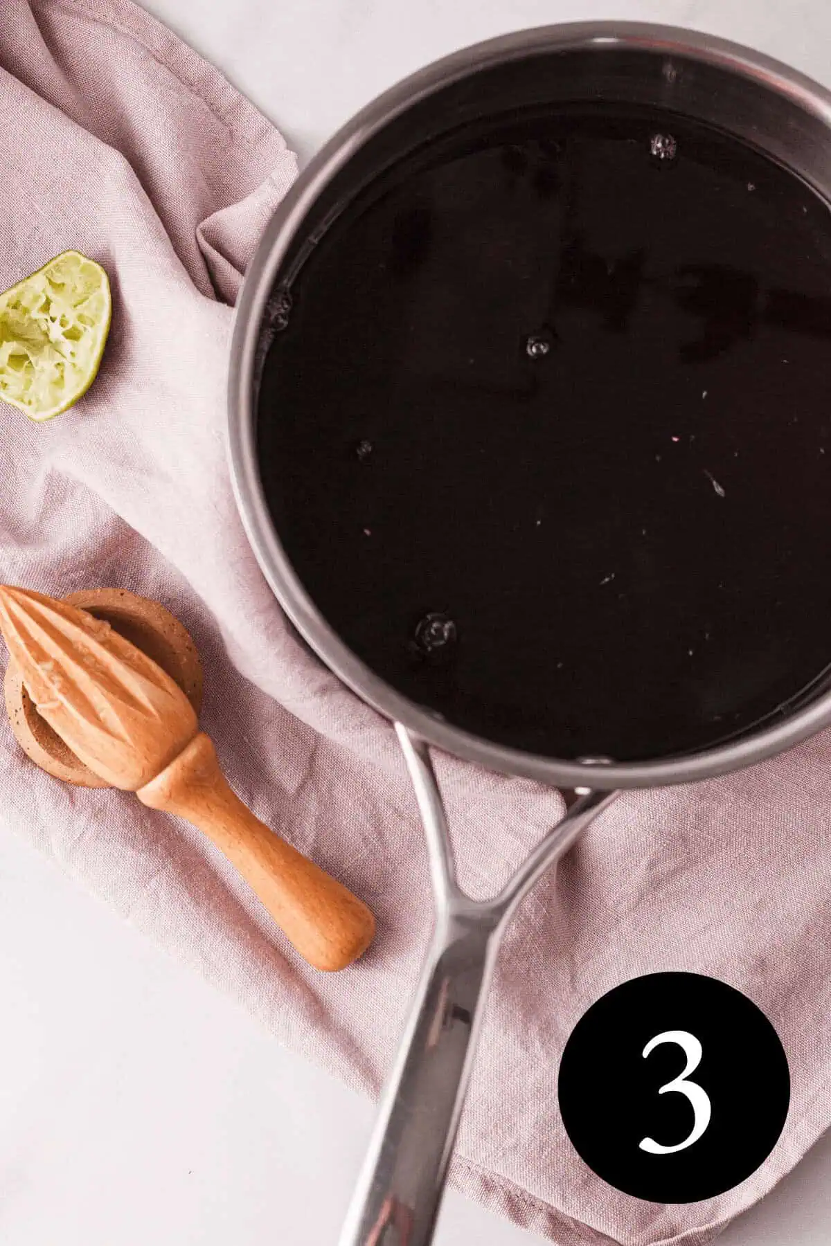 overhead image of hibiscus tea in saucepan next to citrus juicer and lime half on counter and number three in bottom right corner
