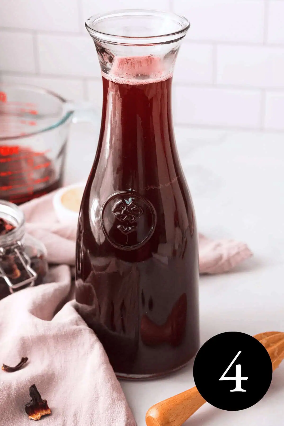 closeup of hibiscus tea with cinnamon in glass carafe and number four in the bottom right corner