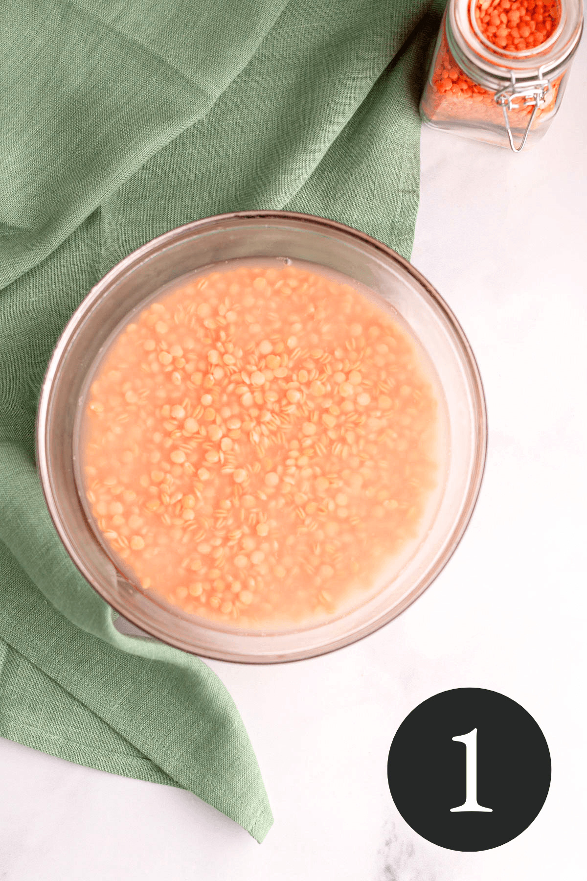 overhead image of red lentils soaking in a bowl of water with number one in bottom right corner
