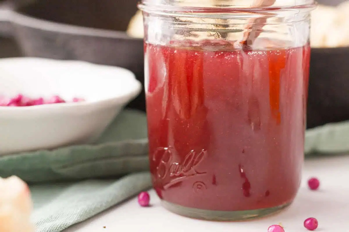 closeup of beautyberry jelly in jar with berries in foreground and background
