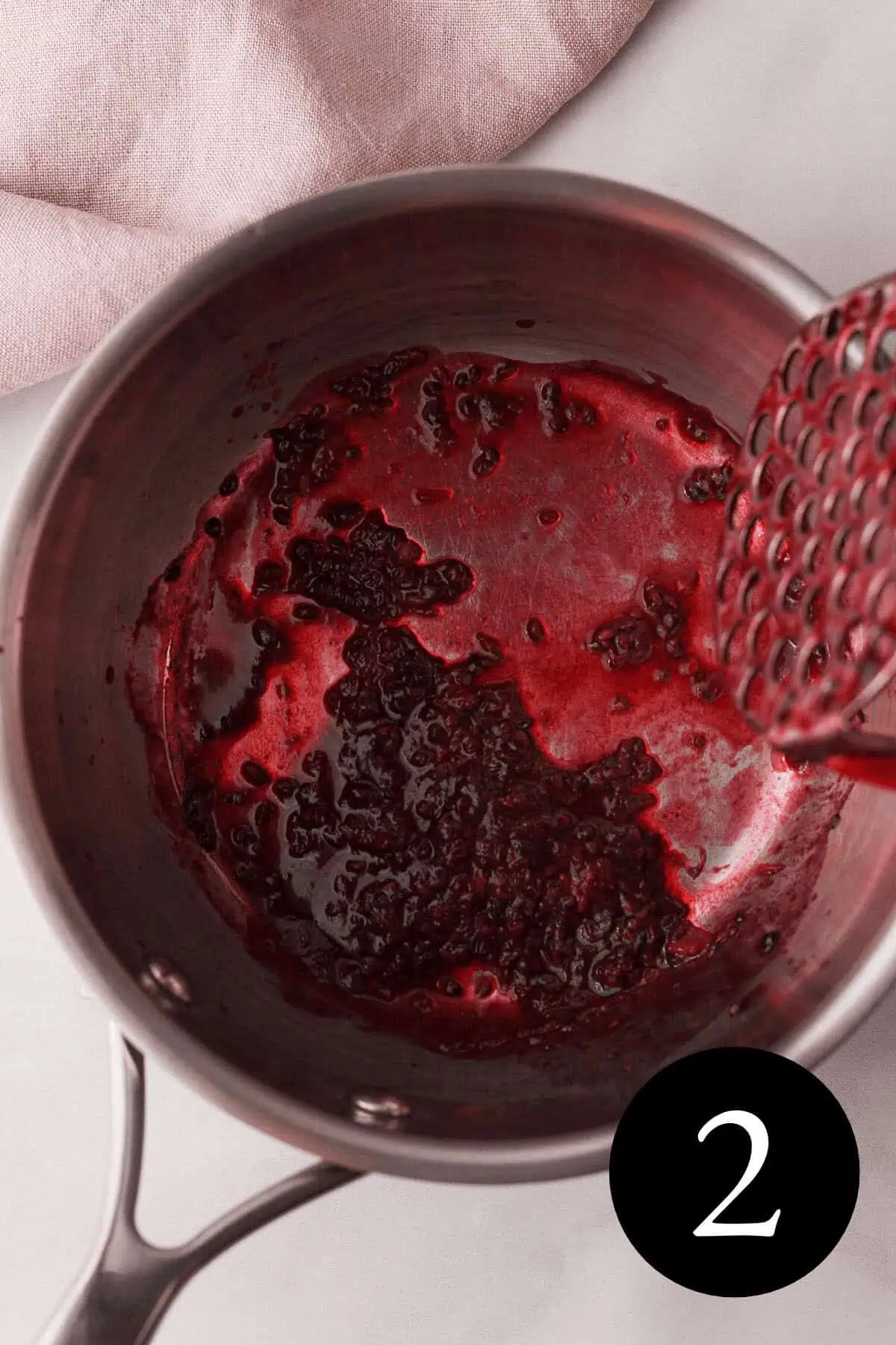 overhead image of mashed blackberries in saucepan with number two in bottom right corner