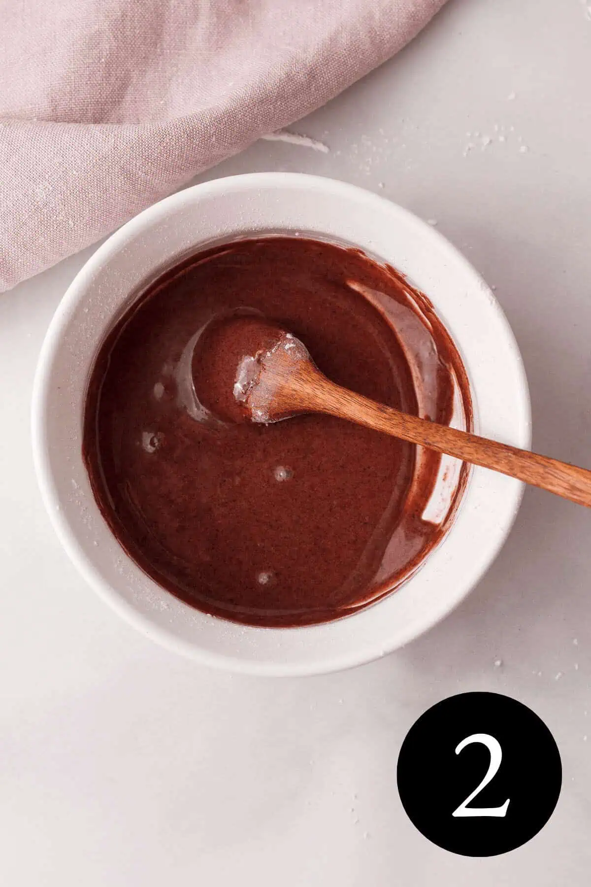 overhead image of blackberry icing glaze in white bowl with spoon and number two in bottom right corner