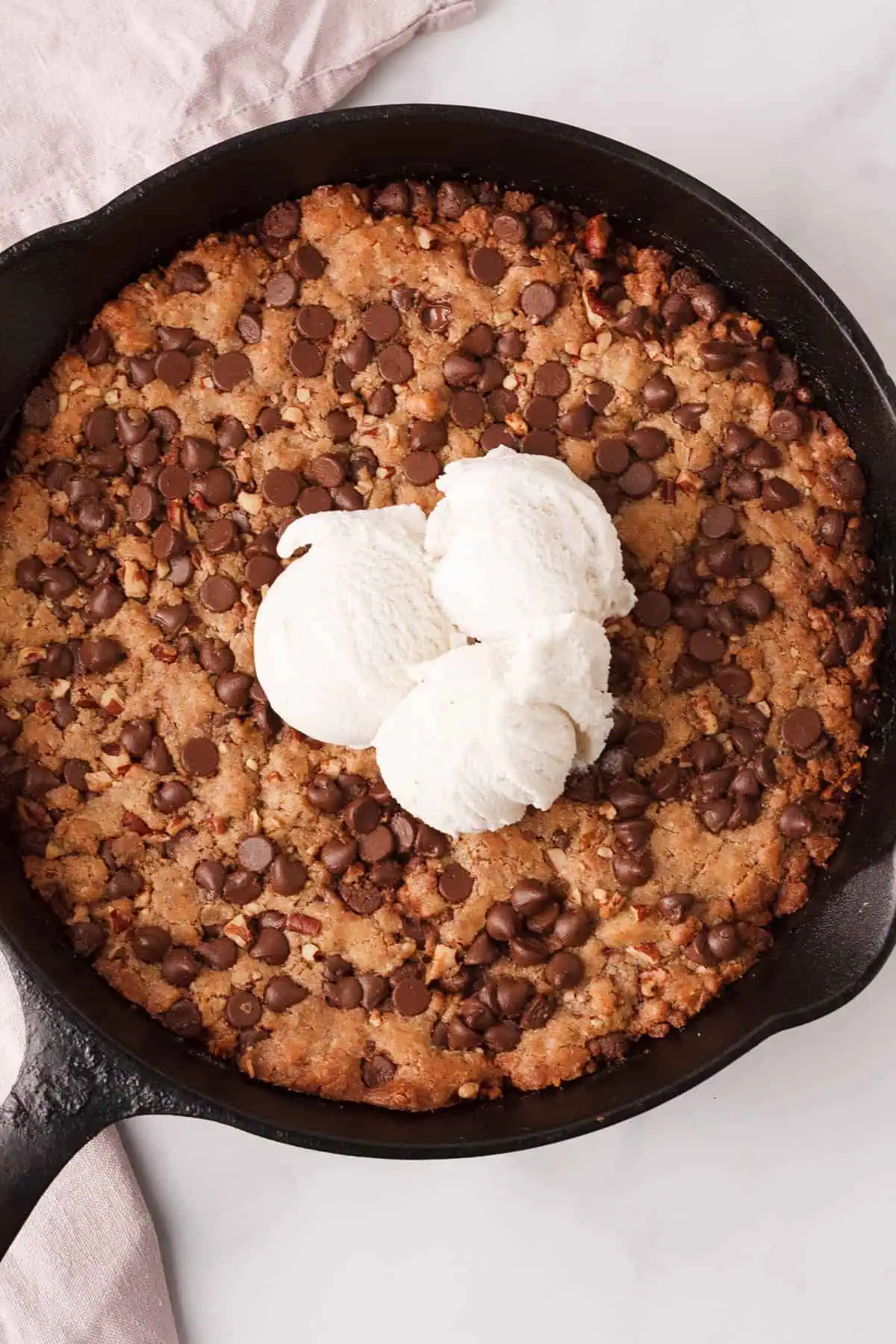 overhead image of cast iron skillet cookie cake topped with ice cream in skillet