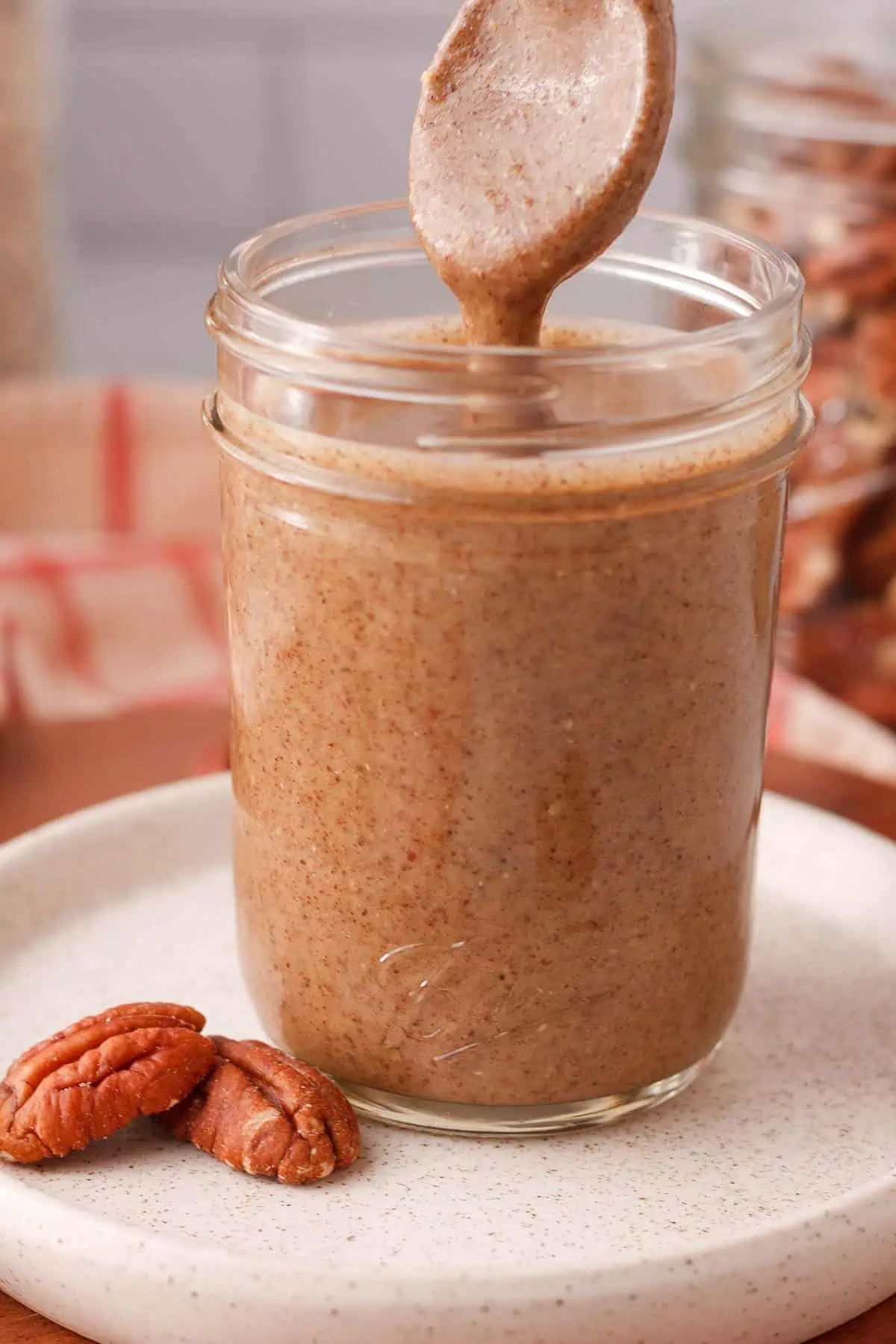 spoon emerging from jar of pecan butter