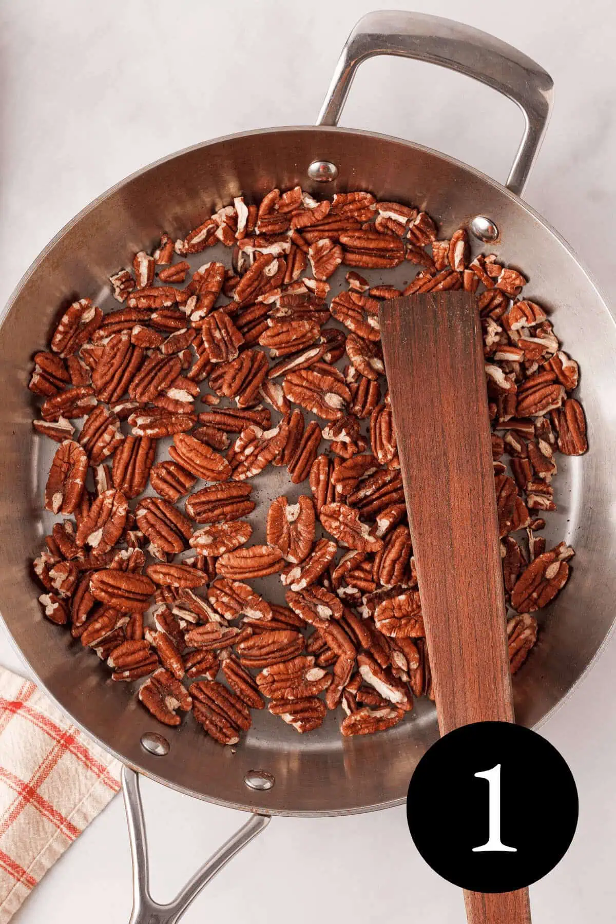 overhead image of pecans roasting in skillet with number one in the bottom right corner