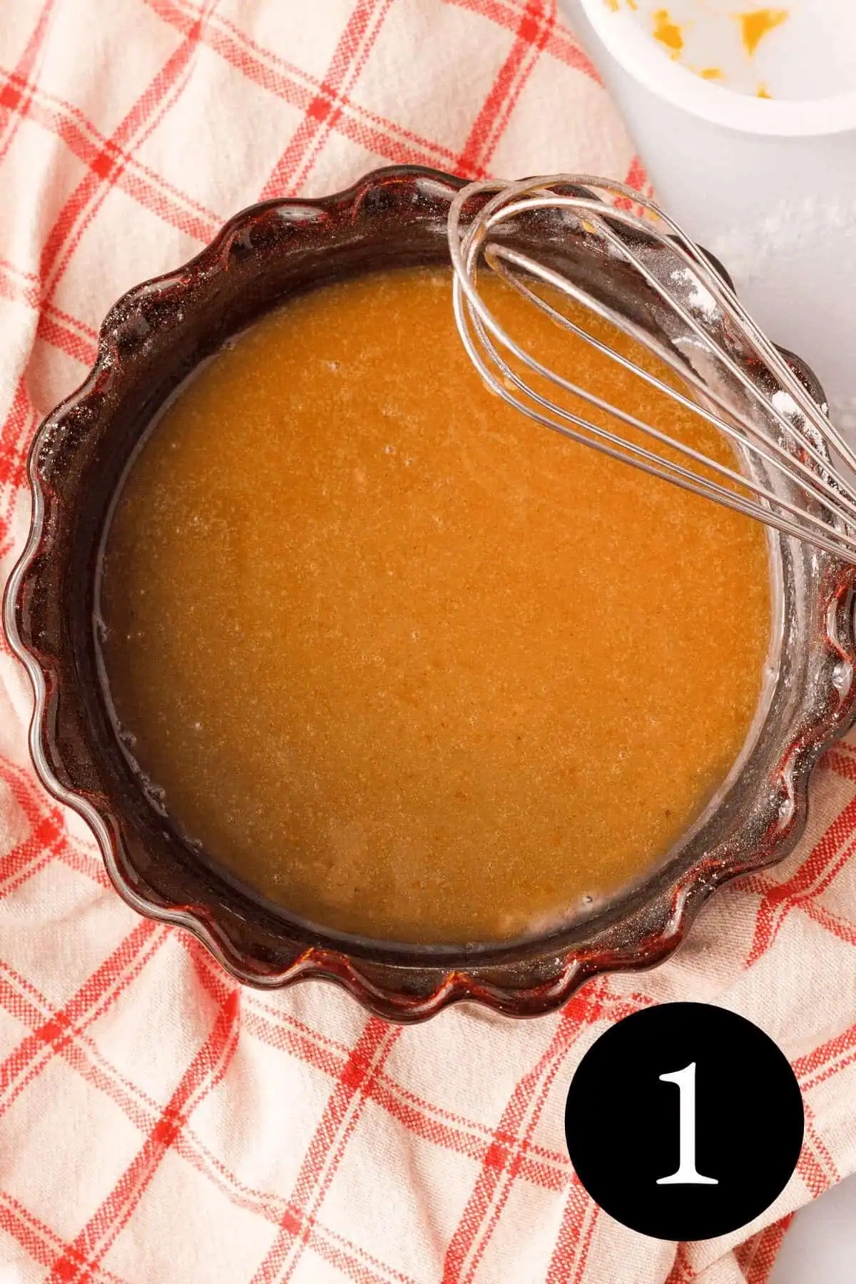 overhead image of pumpkin icing glaze in bowl with whisk and number one in the bottom right corner