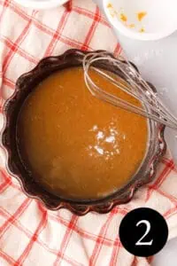 overhead image of pumpkin icing glaze in bowl with whisk propped on the side and number two in the bottom right corner