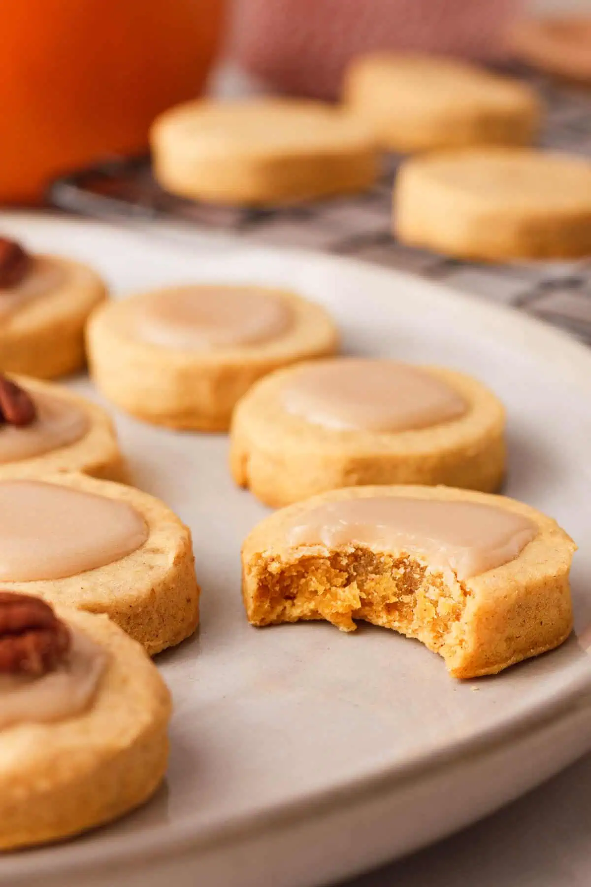 plate of pumpkin shortbread cookies showing a cookie in the foreground with bite removed