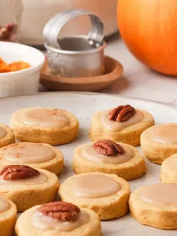 iced pumpkin shortbread cookies on plate with ingredients in the background